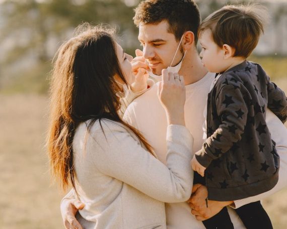 Family sharing affectionate moments outdoors with parents and child enjoying the sunny day.